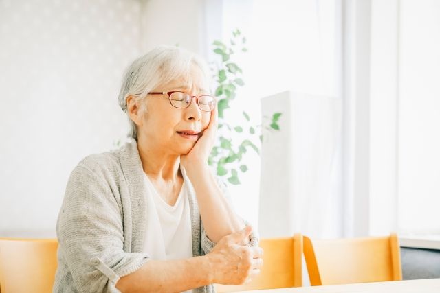 歯の痛みを感じる高齢女性