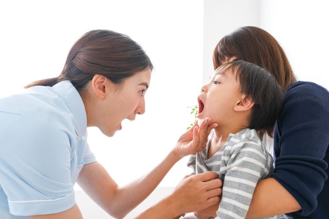 子どもの口内をチェックする女性スタッフ